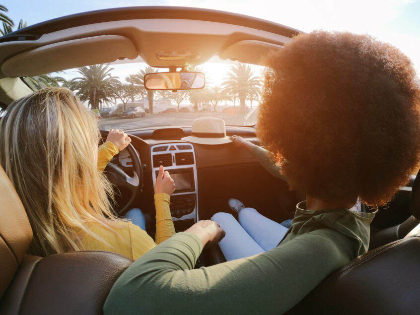 Two people driving happily in their car after receiving their quick title loan. California Title Loans concept image.